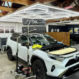 White Toyota RAV4 undergoing paintless dent repair with LED lighting rig at Dent Devils workshop