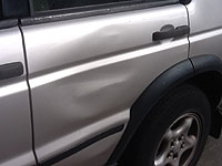 Collision damage to vehicle panel unsuitable for paintless dent removal repair